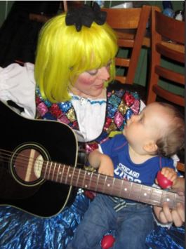 A woman holding a baby and playing an instrument