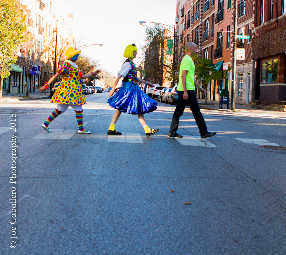 Three people are crossing the street in a parade.