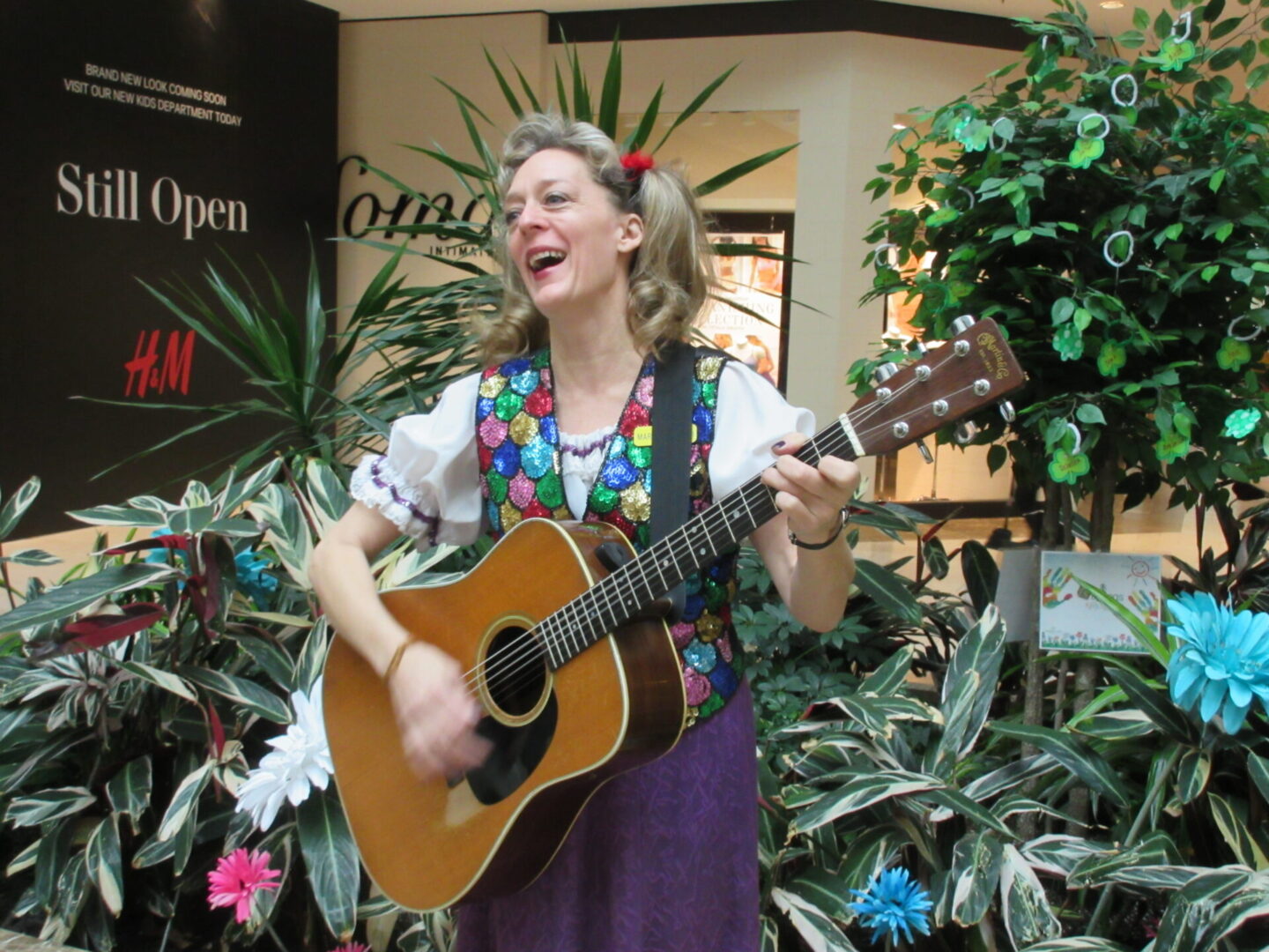 A woman in a floral shirt playing an instrument.