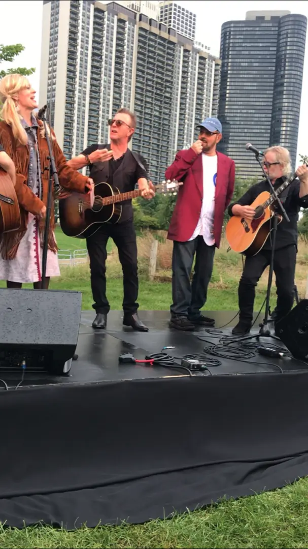 A group of people on stage playing guitar and singing.